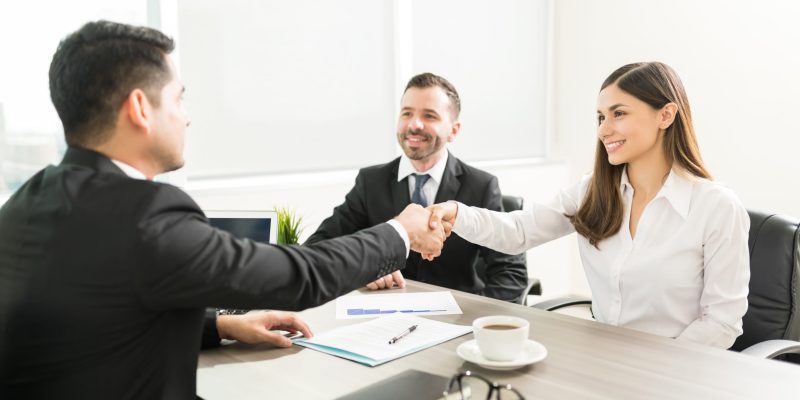 Handshake Over Agreement Of Business Project Smiling businesswoman shaking hand with employee at desk in office